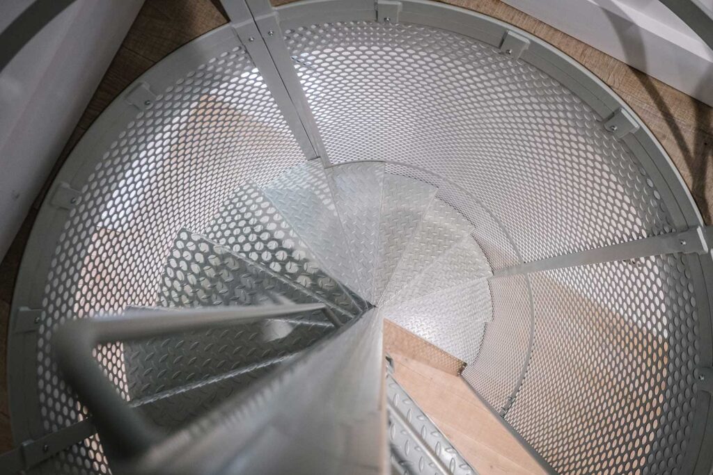 Bespoke metal spiral staircase enclosed in a spherical perforated steel design
