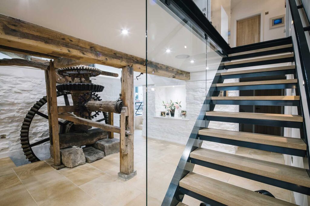 Front view of 1 flight of stairs with a juxtaposition of materials using a metal frame, wood treads and glass panelling