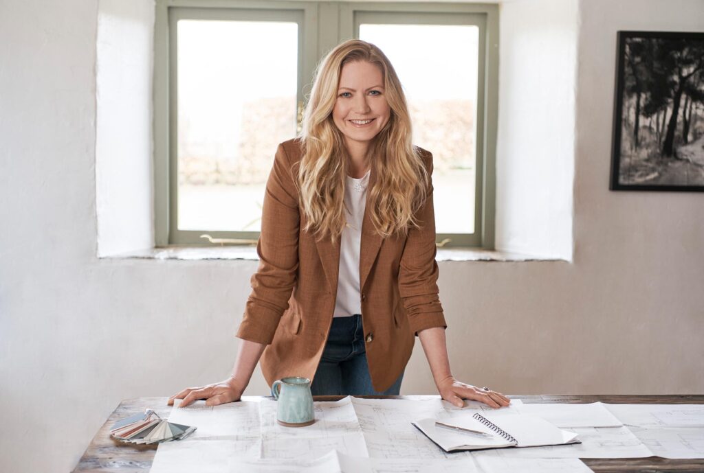 Charlotte Findlater, a luxury and high-end interior designer, standing over a desk of architect drawings