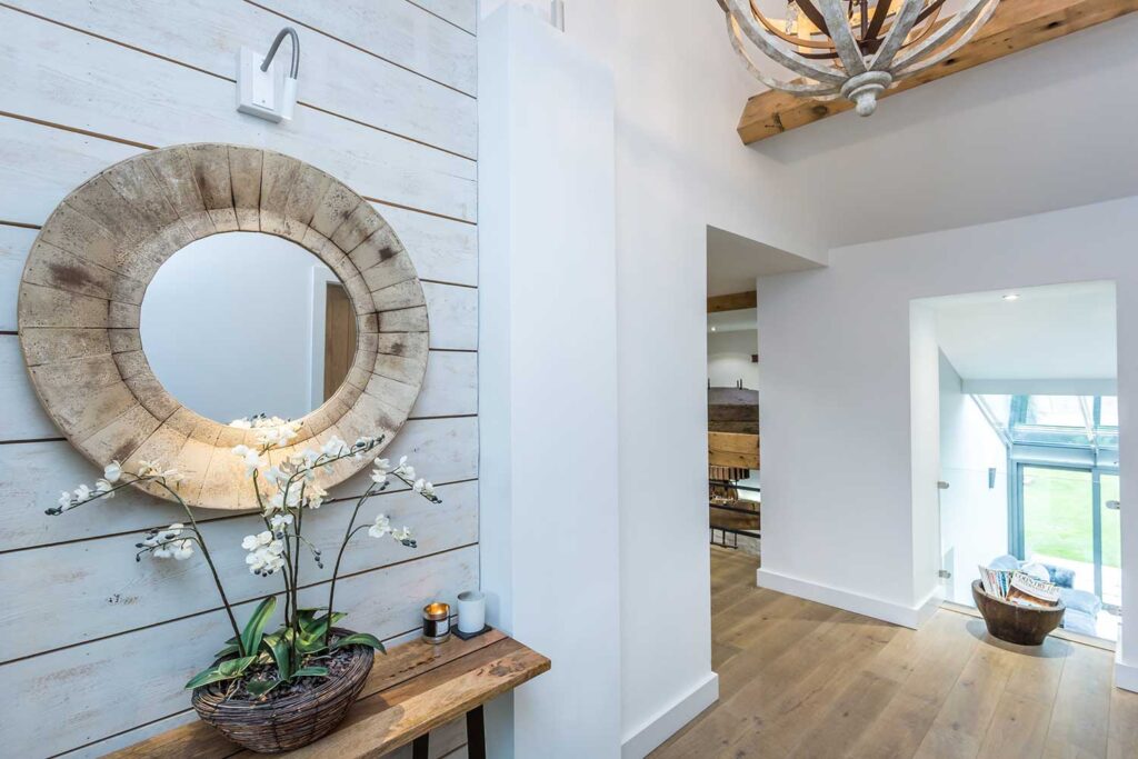 Entrance hall flooded with natural light and a large wall mounted circular mirror