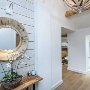Entrance hall flooded with natural light and a large wall mounted circular mirror
