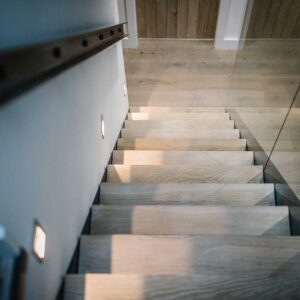 Bespoke commission of a three flights staircase with a juxtaposition of materials using a metal frame, wood treads and glass panelling. Bespoke lighting and matching metal handrail.