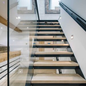 Bespoke commission of a three flights staircase with a juxtaposition of materials using a metal frame, wood treads and glass panelling. Bespoke lighting and matching metal handrail.