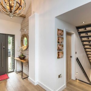 Entrance hall design with wooden flooring and bespoke glass, metal and wood staircase