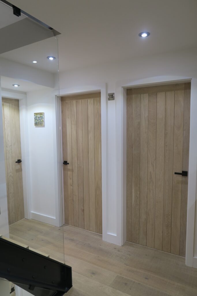 Two handmade wooden doors leading off a wooden floored landing
