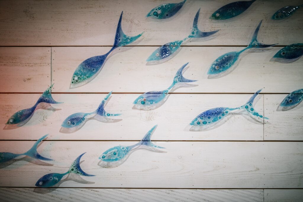 Blue handmade glass fish wall mounted on wood cladding