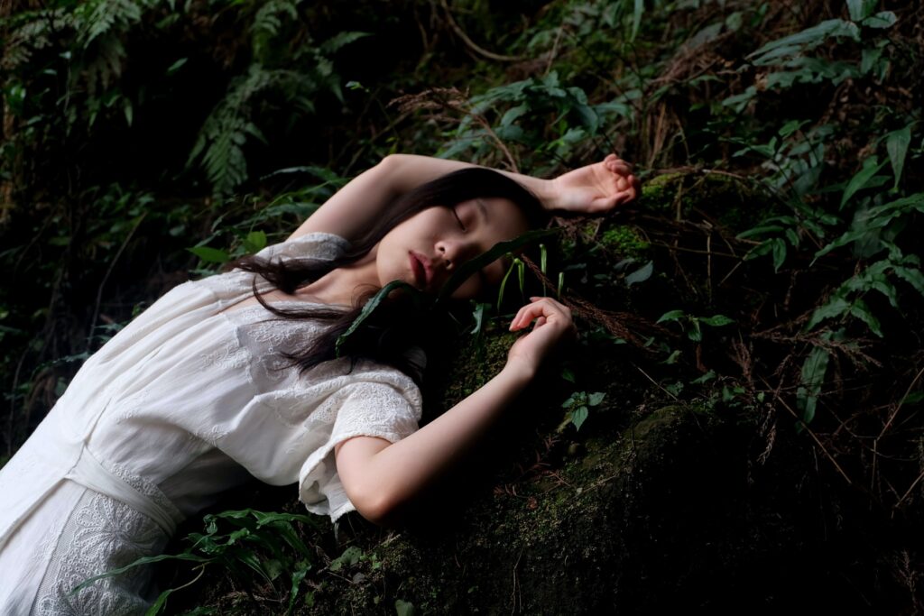 A lady in a white dress dress sleeping on the earthy ground