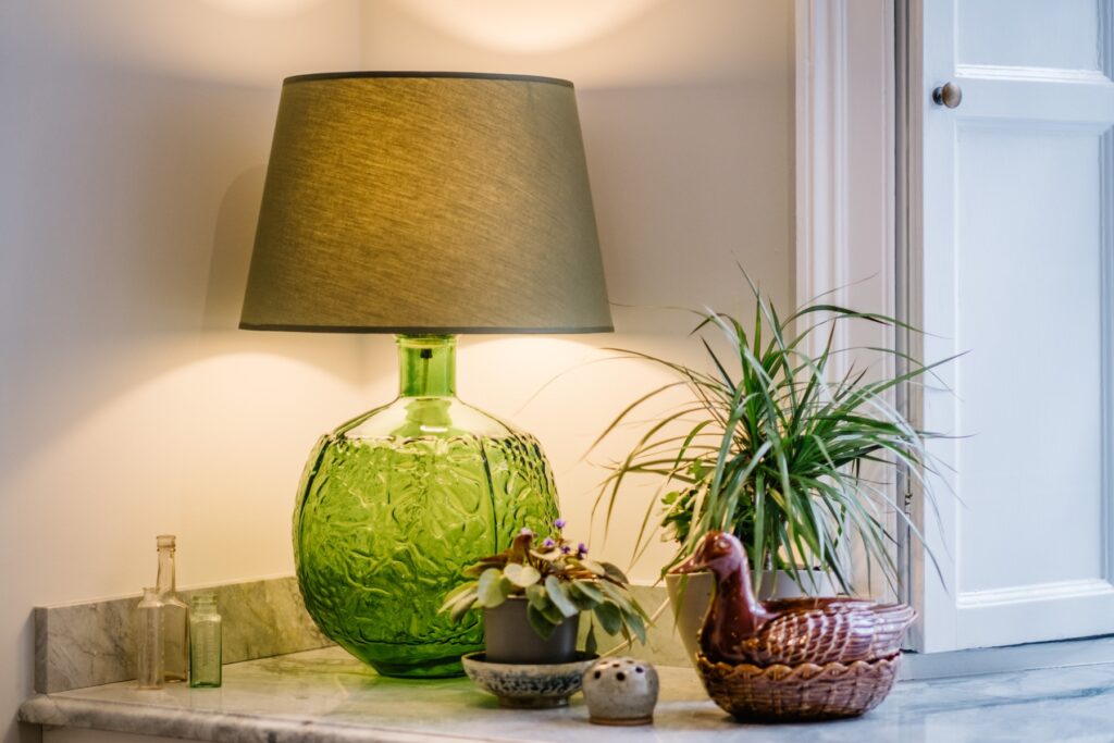Close up of green lamp, flowers and duck egg holder on a marble kitchen top