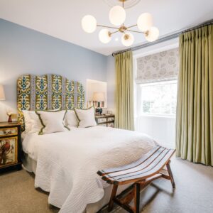 Bedroom with a nature inspired green and white calming theme, view of the double bed, curtains, pendant light and full height curtains