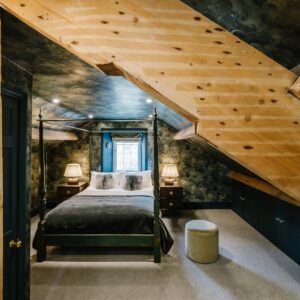 View through a beam of an attic bedroom conversion with a stars and skies theme and four poster bed