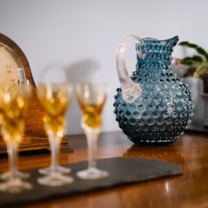 Close up of handmade glass water jug sitting on a dining room console