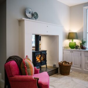 Close of reupholstered natural fabric chair and roaring log burner