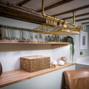 Close up on shelving with decorative ornaments and gold coloured hangers in a luxury laundry room