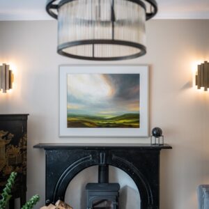 Close up of log burner, fire surround and landscape art on the wall
