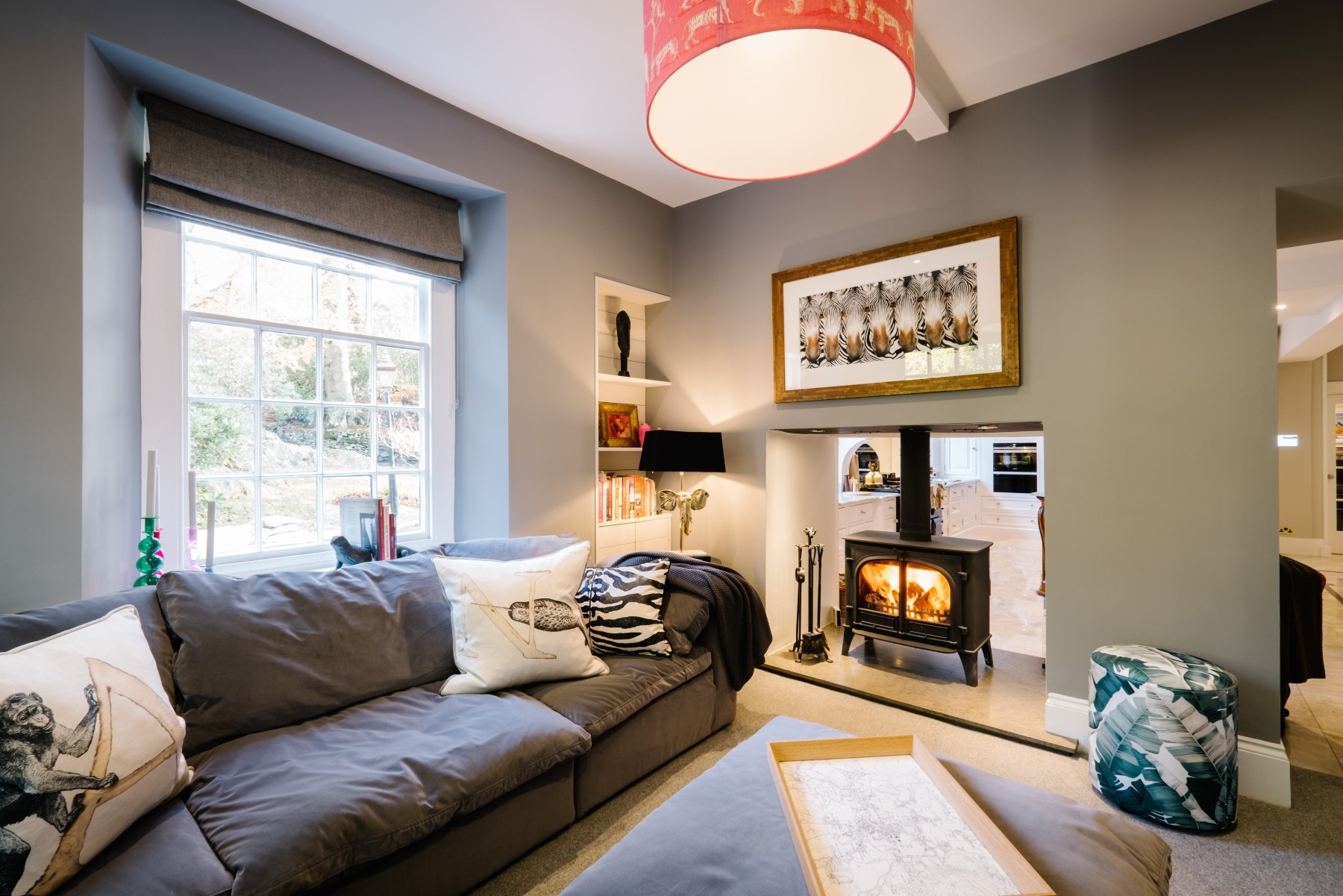 Lounge with sofas, lit log burner and a view outside