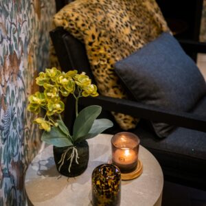 Close up of inside flower and candle on a table next to a study chair