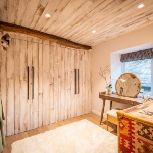 Dressing room with bespoke clad wardrobes, wood flooring in a Scandi style