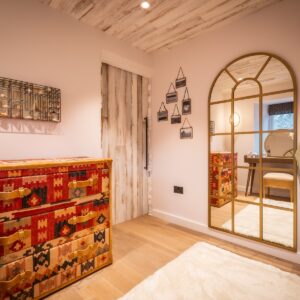 Dressing room with artisan drawers, full height arched mirror and dressing gown hung on the wall