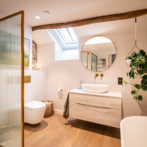 Biophilic designed ensuite bathroom with gold framed ribbed glass shower screen and white vanity unit