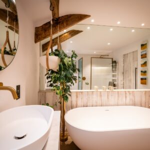 Biophilic designed ensuite bathroom with white sink and gold taps, white bath and large wall mirror