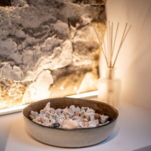 Exposed stone wall with custom lighting and handmade bowl of shells in a Biophilic designed ensuite bathroom