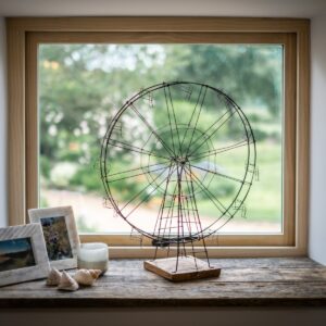 Close up of reclaimed wood window sill with a handmade wire ferris wheel ornament