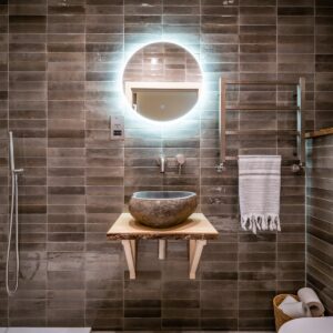 Luxury ensuite bathroom infused with natural materials with a stone pebble sink set on a rustic wooden plinth