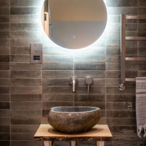 Luxury ensuite bathroom close up of a stone pebble sink set on a rustic wooden plinth