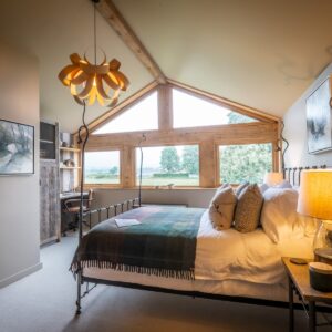 Bedroom with a double bed side on and Oak framed window wall