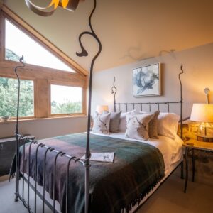 Bedroom with a double bed side on and Oak framed window wall