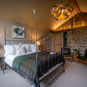 Bedroom with a double bed side on, an exposed stone wall with led lighting