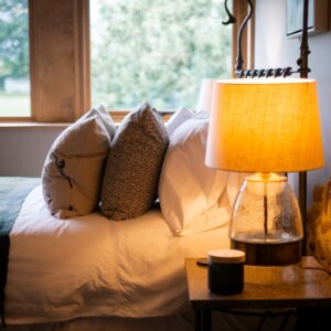 Close up on the bedside table with lamp and side view of the bed cushions in a bedroom