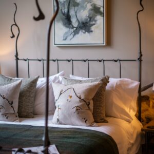 Close up on Joanna Farrow artwork and a made bed with cushions