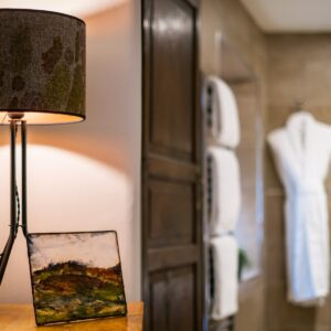 Close up of a bedside table lamp with dressing gowns in the background