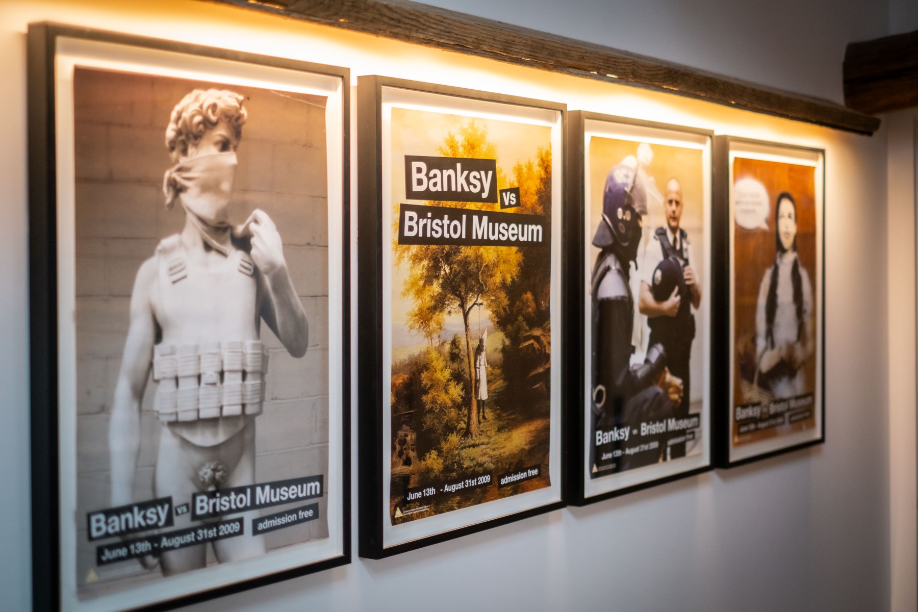 Banksy vs Bristol Museum original posters, framed, wall hung and lit overhead