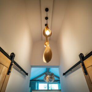 Hallway to a master bedroom with sliding oak doors and oak bent pendant lights