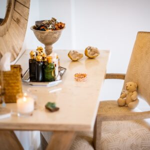 Close up of a dressing table with wall mounted mirror, jewellery box and perfumes set out on the dressing table