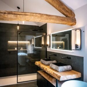 Luxury ensuite bathroom with natural stone tiling, stone basins and Oak truss