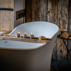 Close up on a freestanding bath with a craftsman made bath table with lit candles on it