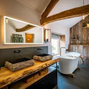 Luxury ensuite bathroom with natural stone tiling, stone basins and white slipper bath