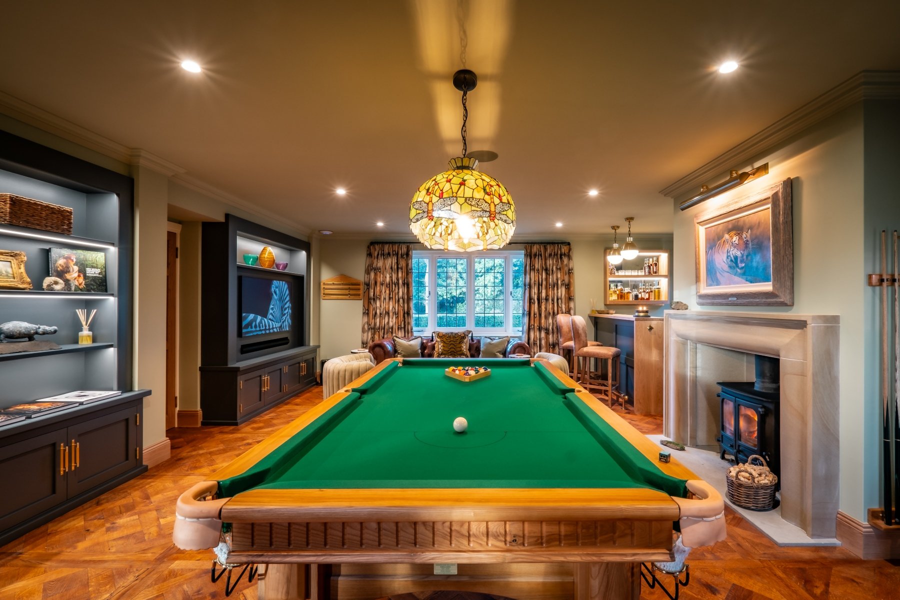 Luxury games room with bespoke Oak pool table, parquet flooring, stone fireplace, built ins and media wall