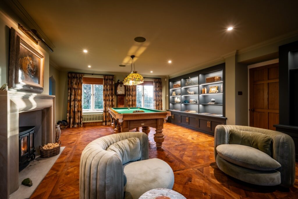 Luxury games room with bespoke Oak pool table, bar, media wall and stone fireplace designed and built by Charlotte Findlater Design, an award winning interior design studio specialising in luxury, high-end residential & commercial projects that respect time, nature and people.