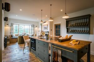 The island unit of a farmhouse style kitchen is the main focus. it has a bespoke Oak worktop and Copper worktop. There is a bespoke wall mounted plate rack. You can see the terracotta floor tiles.