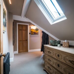 Hallway entrance to the principle bedroom with an antique drawer set and Velux window