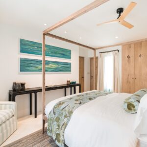 A guest bedroom with a feature wooden four poster bed, 2 original hand painted fish painting on the wall, a view of the hand made wooden wardrobes