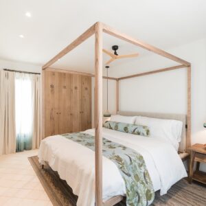 A guest bedroom with a feature wooden four poster bed and a view of the hand made wooden wardrobes