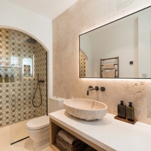 The ensuite with a walk in shower with Menorcan hand made square tiles with an 8 pointed star in yellow and blue colours, natural stone tiling behind the hand carved stone sink, and a large wall mounted mirror