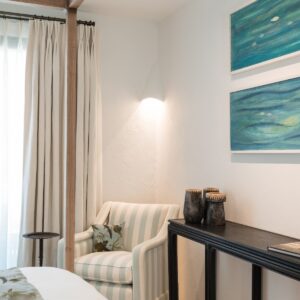 A close up of the aqua and white strip single chair with a hand made real leaf printed cushion and a glimpse of the 2 original wall hung hand painted fish paintings
