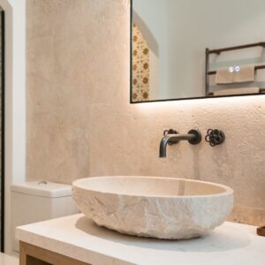 A close up of the hand carved stone sink and vanity mirror with its led lighting on