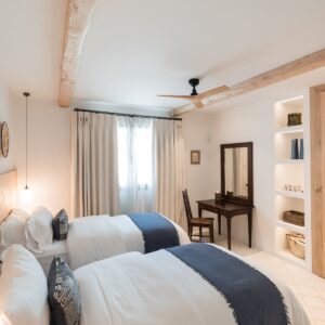 A twin bedroom with marez flooring, hand made wardrobes and an antique desk, mirror and chair in the corner by the windows